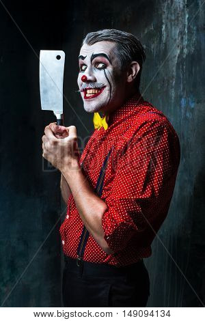 The scary clown holding a knife on dack. Halloween concept of horror and murderer