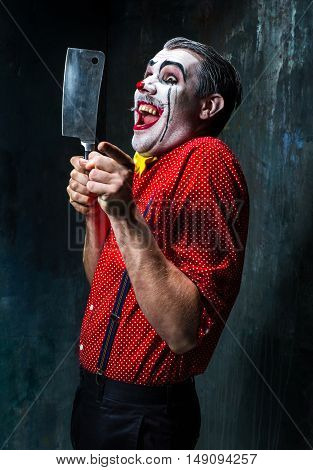 The scary clown holding a knife on dack. Halloween concept of horror and murderer