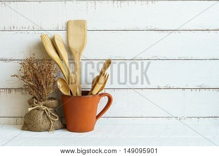 Kitchen cooking utensils on a shelf with white rustic wooden background