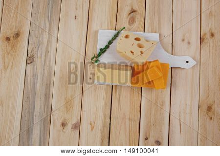various types of fresh raw aged delicatessen cheese on white plate over light wooden table cheddar edam swiss