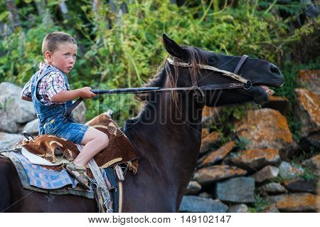 Ushguli Georgia - August 15 2016: Color image of a young boy riding a horse in the Caucasian village of Ushguli Georgia.