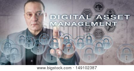 Mature corporate system administrator with concentrated gaze is pressing DIGITAL ASSET MANAGEMENT onscreen. Business concept for information technology management and content management systems.