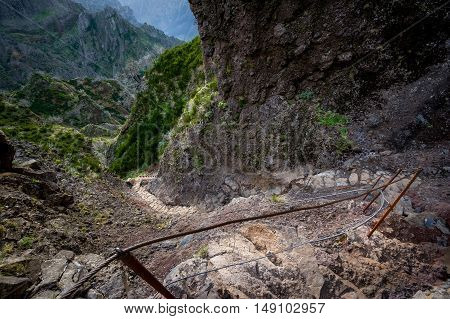 Steep stone stair in the rocky path from Pico Ruivo. Backlit mountain landscape and dangerous path between the rocks. Madeira island, Portugal.