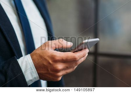 Close up of male hand holding smartphone. Business and telephone, communication, modern technology concept.