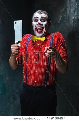 The crazy clown holding a knife on dack. Halloween concept of horror and murderer