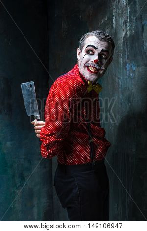 The crazy clown holding a knife on dack. Halloween concept of horror and murderer