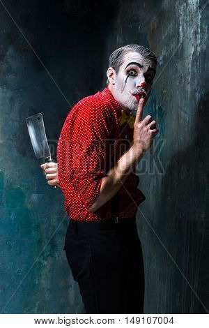 The crazy clown holding a knife on dack. Halloween concept of horror and murderer