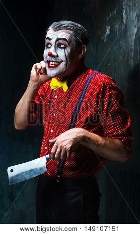 The crazy clown holding a knife on dack. Halloween concept of horror and murderer