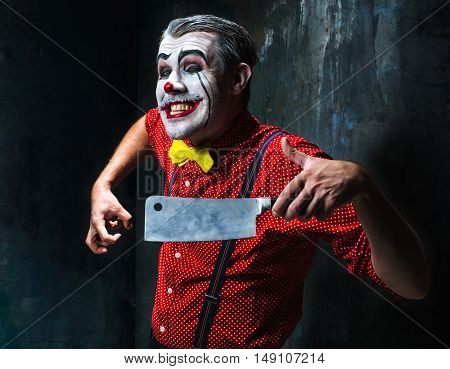 The crazy clown holding a knife on dack. Halloween concept of horror and murderer
