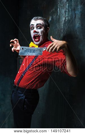 The crazy clown holding a knife on dack. Halloween concept of horror and murderer