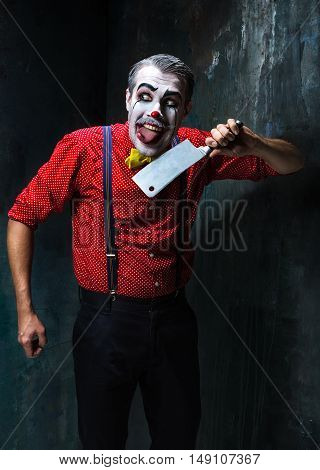 The crazy clown holding a knife on dack. Halloween concept of horror and murderer