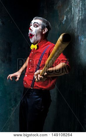 The scary clown and baseball-bat on dack. Halloween concept of horror and murderer