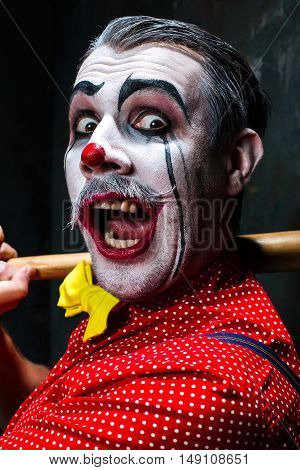 The scary clown and baseball-bat on dack. Halloween concept of horror and murderer