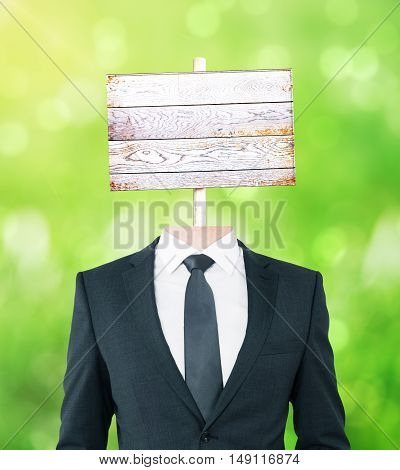 Young businessman body with wooden signboard instead of head on green background. Mock up