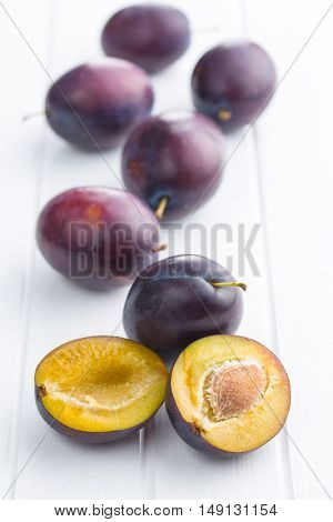 Halved ripe plum on white table.