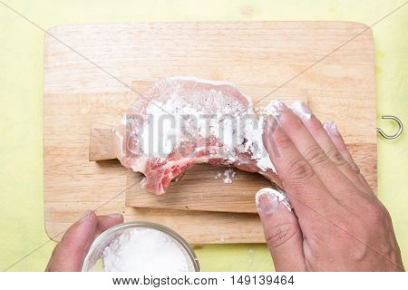 Chef putting flour to raw porkchop / cooking porkchop steak concept