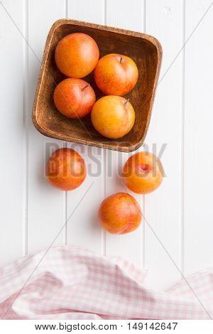 Fresh yellow plums on white table. Top view.