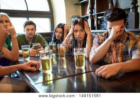 people, leisure, friendship and entertainment concept - friends drinking beer and watching sport game or football match at bar or pub