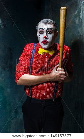 The scary clown and baseball-bat on dack. Halloween concept of horror and murderer