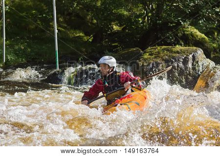 BALA WALES UNITED KINGDOM SEPTEMBER 17 2016: White water kayaker at the National White Water Centre canoeing through rapids on the River Tryweryn