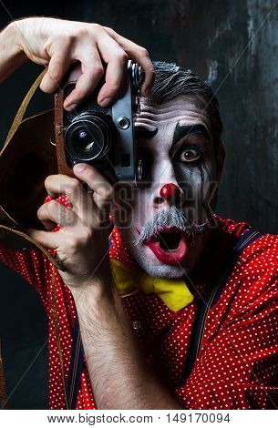 The scary clown and a camera on dack. Halloween concept of horror and murderer