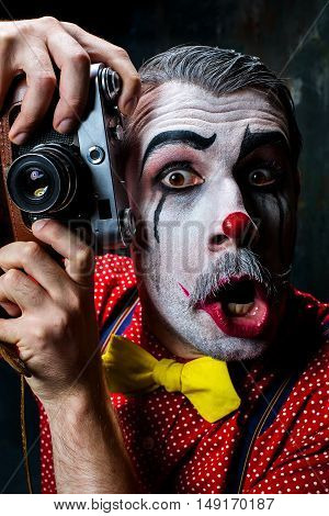 The scary clown and a camera on dack. Halloween concept of horror and murderer
