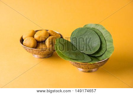 indian festival dussehra or vijayadashmi or ayudh puja, showing apta leaf or Bauhinia racemosa with traditional indian sweets pedha in silver bowl