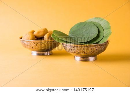 indian festival dussehra or vijayadashmi or ayudh puja, showing apta leaf or Bauhinia racemosa with traditional indian sweets pedha in silver bowl