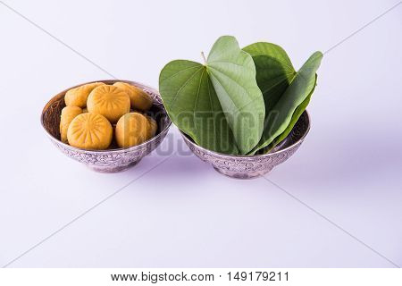 indian festival dussehra or vijayadashmi or ayudh puja, showing apta leaf or Bauhinia racemosa with traditional indian sweets pedha in silver bowl