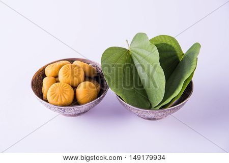 indian festival dussehra or vijayadashmi or ayudh puja, showing apta leaf or Bauhinia racemosa with traditional indian sweets pedha in silver bowl