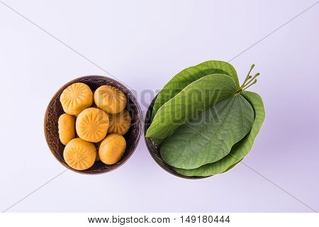 indian festival dussehra or vijayadashmi or ayudh puja, showing apta leaf or Bauhinia racemosa with traditional indian sweets pedha in silver bowl