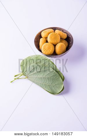 indian festival dussehra or vijayadashmi or ayudh puja, showing apta leaf or Bauhinia racemosa with traditional indian sweets pedha in silver bowl