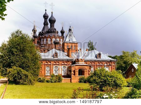 A beautiful Orthodox temple located on a hill surrounded by flowers and plants: arborvitae blue spruce shrubs.
