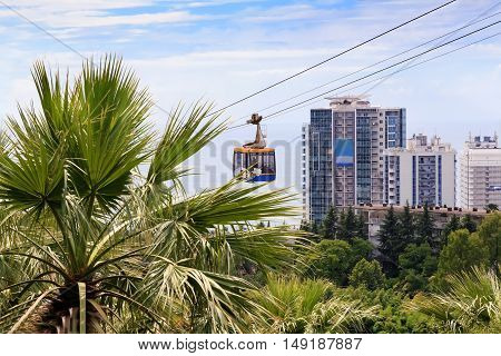 Cable car with a trailer over the picturesque arboretum in the resort town.
