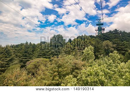 Cable car with a trailer over the picturesque arboretum in the resort town.
