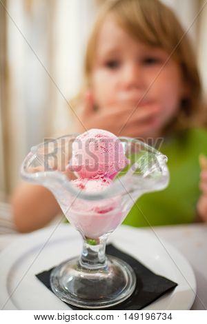 Scoops Of Strawberry Ice Cream In Crystal Cup And Child Behind