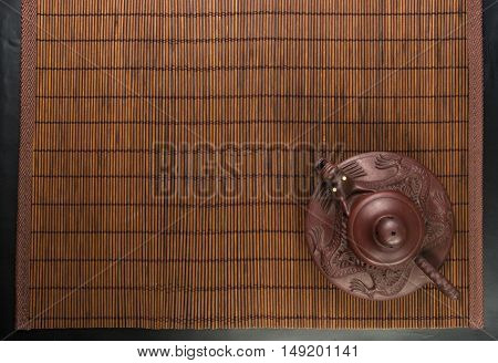 brown Chinese teapot of Yixing clay with traditional ornament on bamboo Mat