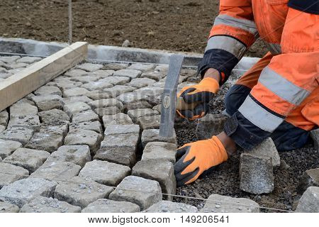Workers sets painstakingly and accurately cobblestone - closeup
