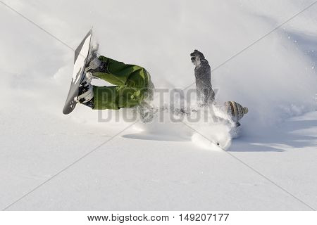 Snowboarder falls on fresh snow on sunny day