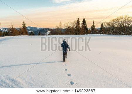 Winter evening. Boy running on snow-covered field. Karpaty Ukraine