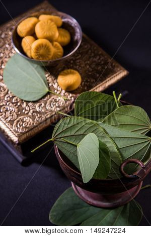 indian festival dussehra or vijayadashmi or ayudh puja, showing apta leaf or Bauhinia racemosa with traditional indian sweets pedha in silver bowl