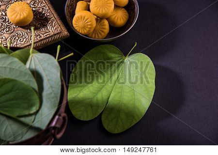 indian festival dussehra or vijayadashmi or ayudh puja, showing apta leaf or Bauhinia racemosa with traditional indian sweets pedha in silver bowl