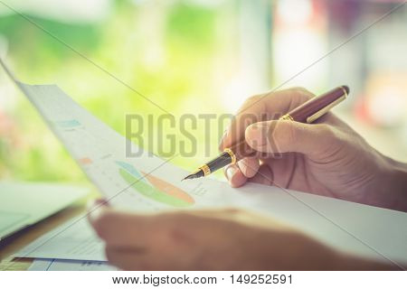 hand hold fountain pen pointing stock maket paper in office. vintage effect.