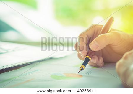 hand hold fountain pen pointing stock maket paper in office. vintage effect.