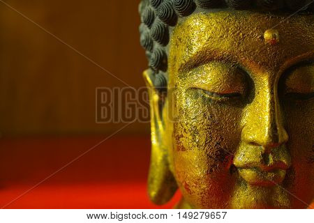 Gold Buddha face on dark red background