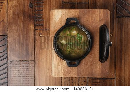 Cooked meat dumplings (pelmeni, chuchpara) in a black pan. wooden background.
