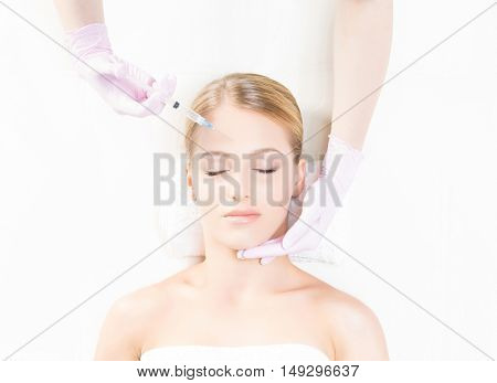 Doctor injecting in a beautiful face of a young woman. Plastic surgery concept.