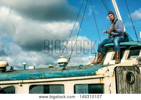 Old salt man playing guitar on his rusted ship