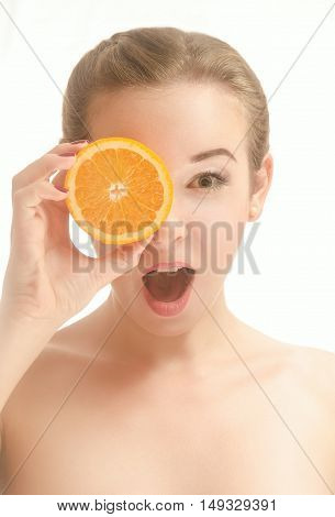 Surprised beautiful young woman holding a slice of orange in front of my eyes. White background