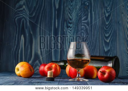 Glass With Calvados Brandy And Yellow Apples On A Wooden Table